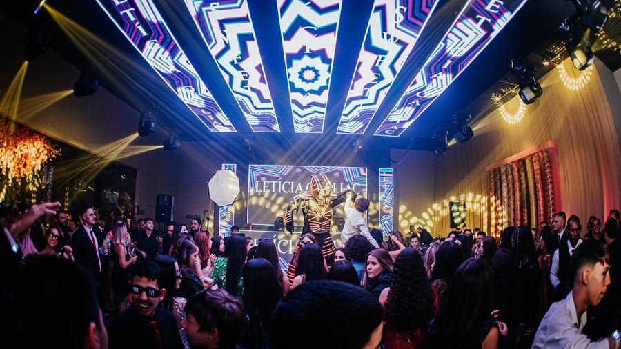 Pista cheia sob painel de LED em festa de 15 anos.