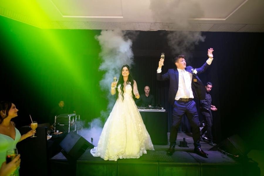 Noivos no palco sob luz verde, em casamento com Edd Barros DJ.