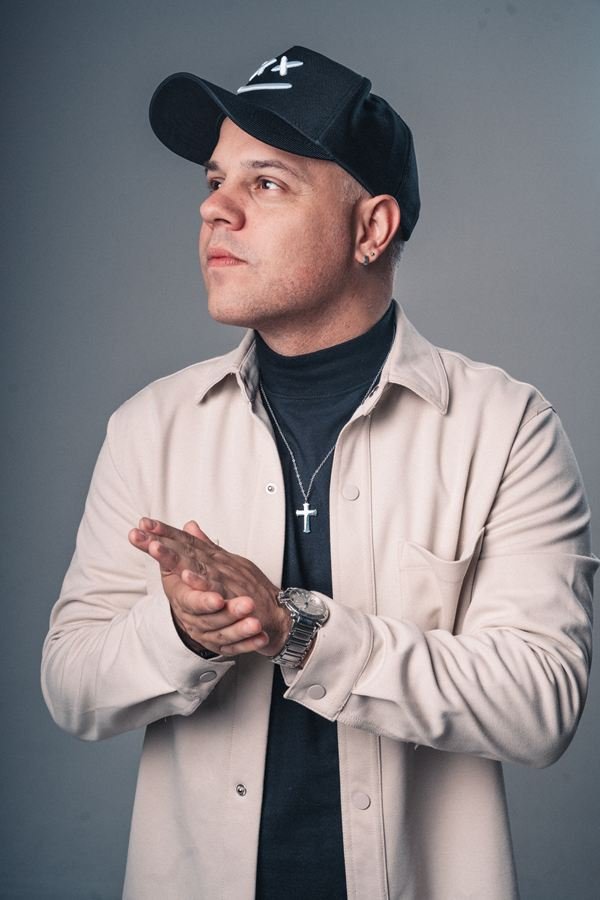 Edd Barros DJ de camisa bege, com as mãos juntas.
