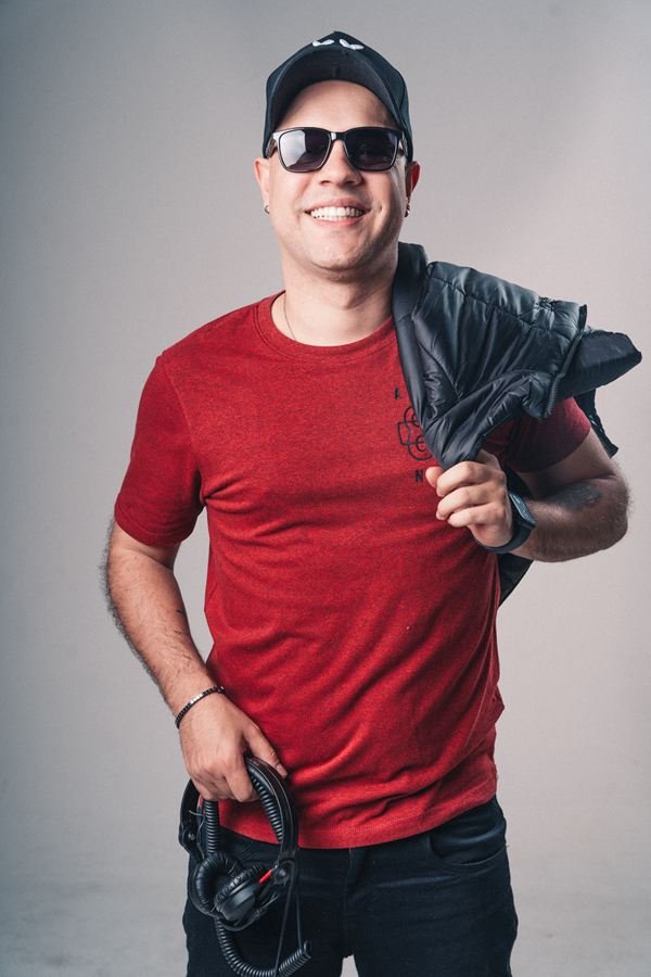 Edd Barros DJ de camiseta vermelha e jaqueta, em retrato de estúdio.