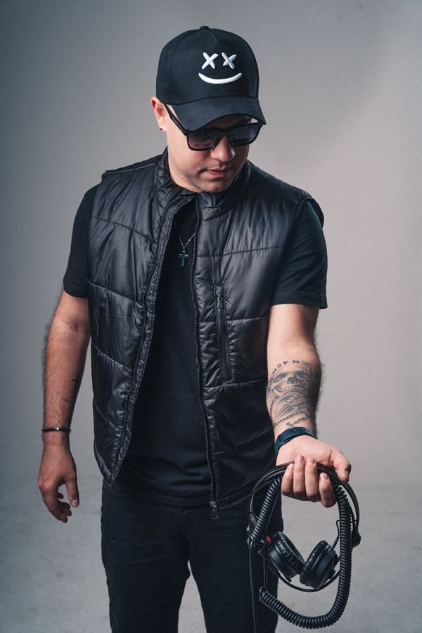 Edd Barros DJ de colete, com o fone na mão.