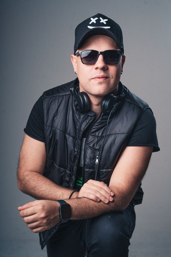 Edd Barros DJ de colete preto, sentado, em retrato de estúdio.