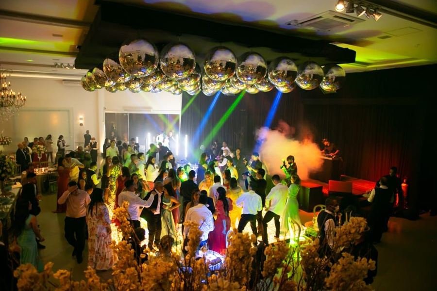 Pista cheia sob globos espelhados, com luz de palco e fumaça colorida.